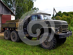 A special-purpose vehicle drives out of the garage, against the backdrop of green spaces and blue sky