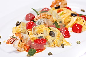 Special shrimp pasta dish made by restaurant chef with tomatoes and olives shot on white background