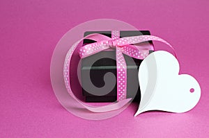 Special small black box present gift with pink polka dot ribbon and white heart shape gift tag