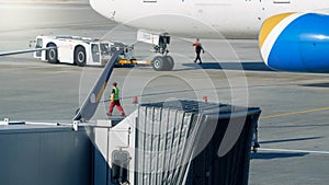 Special tractor pulling big airplane to the boarding gate in airplane terminal