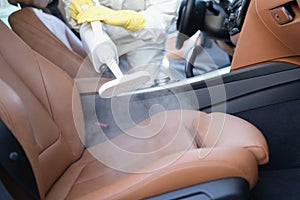 A specialist cleans a car interior with a steam cleaner