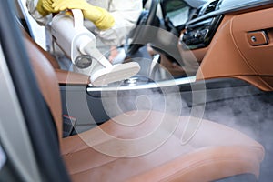 The specialist cleans the chair in the car with a washing vacuum cleaner