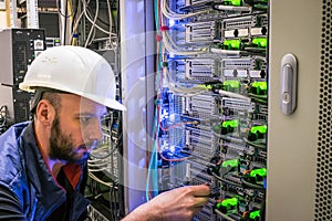A specialist connects the wires in the server room of the data center. A man works with telecommunications. The technician