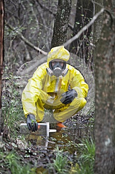 Specialist in coveralls taking sample of water to container