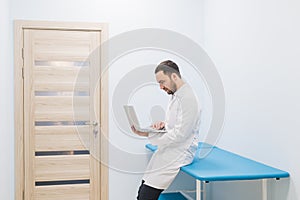 Specialist doctor in the corridor of his clinic with his laptop