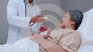 Specialist doctor man checkup with patient elderly with stethoscope for listening heartbeat in hospital ward.