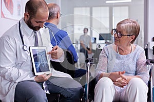 Specialist doctor showing x ray to elderly woman in wheelchair