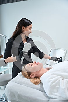 Specialist esthetician adjusts the device for a rejuvenating procedure