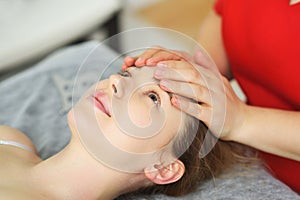 specialist gives a relaxing facial massage to a young woman patient. Facial care