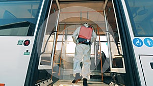 Specialist in a hazmat suit is chemically sterilizing the bus. Coronavirus prevention, epidemic concept.