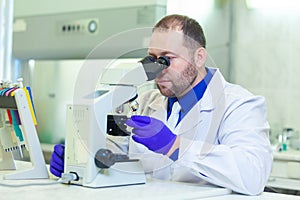 Specialist looking through microscope performing scientific research in a laboratory