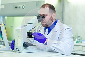 Specialist looking through microscope performing scientific research in a laboratory.