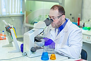 Specialist looking through microscope performing scientific research in a laboratory. Urine test. COVID-19. COVID