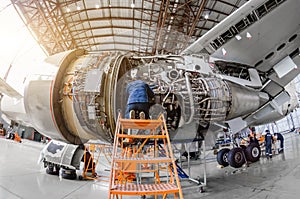 Specialist mechanic repairs the maintenance of a large engine of a passenger aircraft in a hangar.