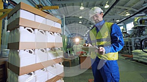 A specialist is observing how plastic canisters are getting wrapped into cellophane