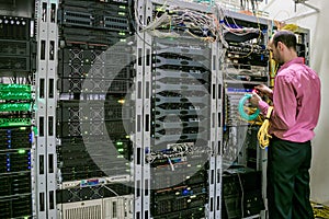A specialist with optical Internet wires works in the server room. The system administrator switches the cables in the data center