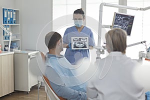 Specialist orthodontist nurse wearing face mask showing teeth radiography