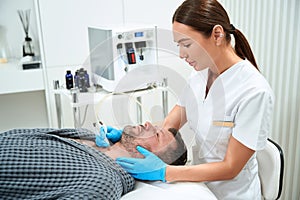 Specialist performs laser microdermabrasion on a middle-aged male