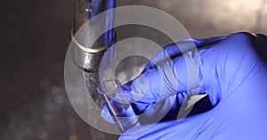 A specialist pours water from a tap into a test tube for chemical analysis of the quality of drinking water