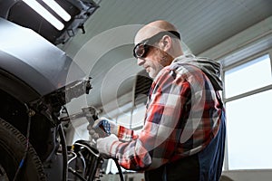 Specialist in protective glasses works as spotter during car repair