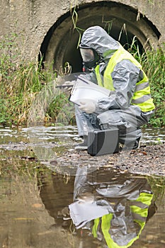 A specialist in a protective suit takes a photo of the place of alleged pollution of the reservoir using a mobile phone
