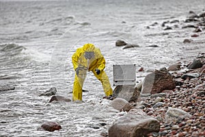 Specialist in protective suit taking sample of water to container