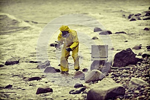 Specialist in protective suit taking sample of water to container