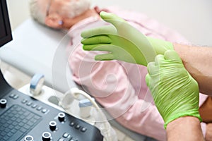 Specialist puts on protective gloves before examining a patient