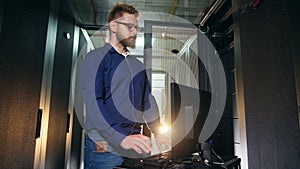 IT specialist, technician is operating a computer in a server unit