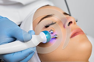 Specialist uses microcurrent massage device on female face