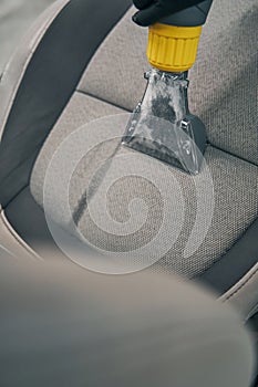 Specialist vacuums removed front seat at car service closeup