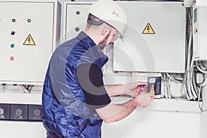 The specialist works with powerful electric boxes. A technician turns off electrical machines near a powerful electrical