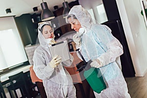 Specialists in protective suits do disinfection or pest control in the apartment
