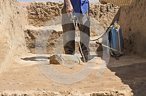 Specialized worker sprays an half-buried bronze piece at archaeological site photo