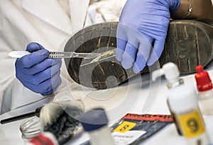 Specializing police officer analyzes ground in a victim`s shoe murder with one tweezers photo