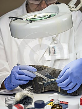 Specializing police officer analyzes ground in a victim`s shoe murder with one tweezers photo