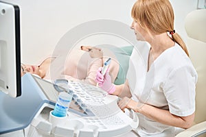 Specially trained woman physician performing ultrasound to adult asian woman