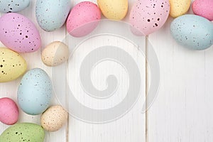 Speckled Easter egg corner border against white wood