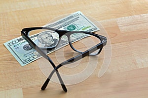 Spectacles with black frame, eye glasses on 20 USD dollar banknote money bill