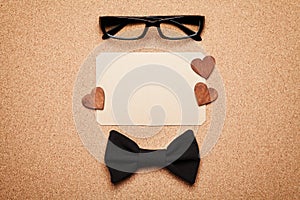 Spectacles, bowtie and empty paper blank in Happy Fathers Day, cork board background, top view, flat lay