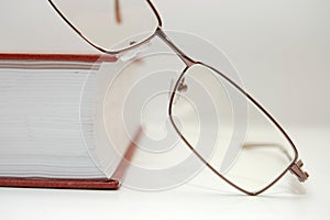 Spectacles laying on the closed book