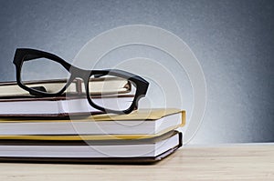 Spectacles on stack of books over beautiful gradient background with reverberation