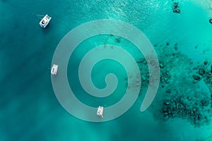 Spectacular aerial view of some yachts and small boats floating on a clear and turquoise sea, Seychelles in the Indian Ocean.Top