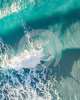 Spectacular aerial view of a surfer taking on waves in a blue ocean