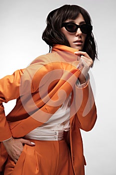 Spectacular beautiful woman in a trendy orange suit with classic make-up. Beauty face.