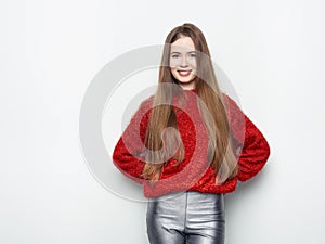 Spectacular blonde woman in red blouse silver leather pants posing in front of white wall. Graceful girl gorgeous long hair having