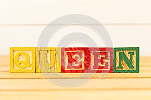Spectacular colorful letters on wooden cubes on a wooden board with the word QUEEN
