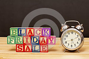 SPECTACULAR CONCEPT OF BLACK FRIDAY AND SALES WITH WOODEN CUBES AND WITH WOODEN SURFACE WITH OLD ALARM CLOCK