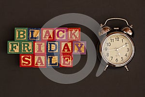 SPECTACULAR CONCEPT OF BLACK FRIDAY AND SALES WITH WOODEN CUBES AND WITH WOODEN SURFACE WITH OLD ALARM CLOCK