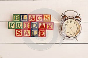 SPECTACULAR CONCEPT OF BLACK FRIDAY AND SALES WITH WOODEN CUBES AND WITH WOODEN SURFACE WITH OLD ALARM CLOCK